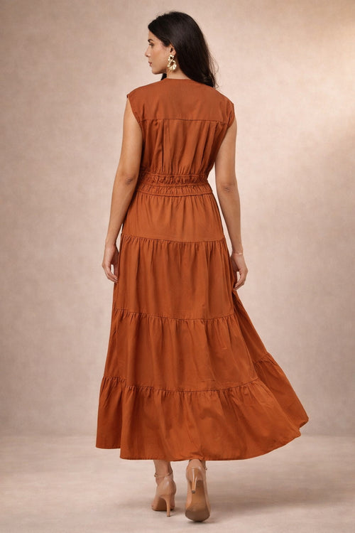 Woman wearing a rust-colored tiered maxi dress against a beige background