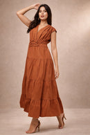 Woman wearing a rust-colored maxi dress against a beige background