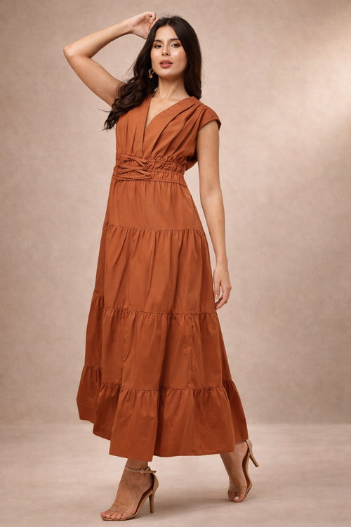Woman wearing a rust-colored maxi dress against a beige background
