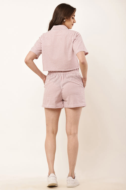 Woman wearing a pink and white checkered outfit on a beige background