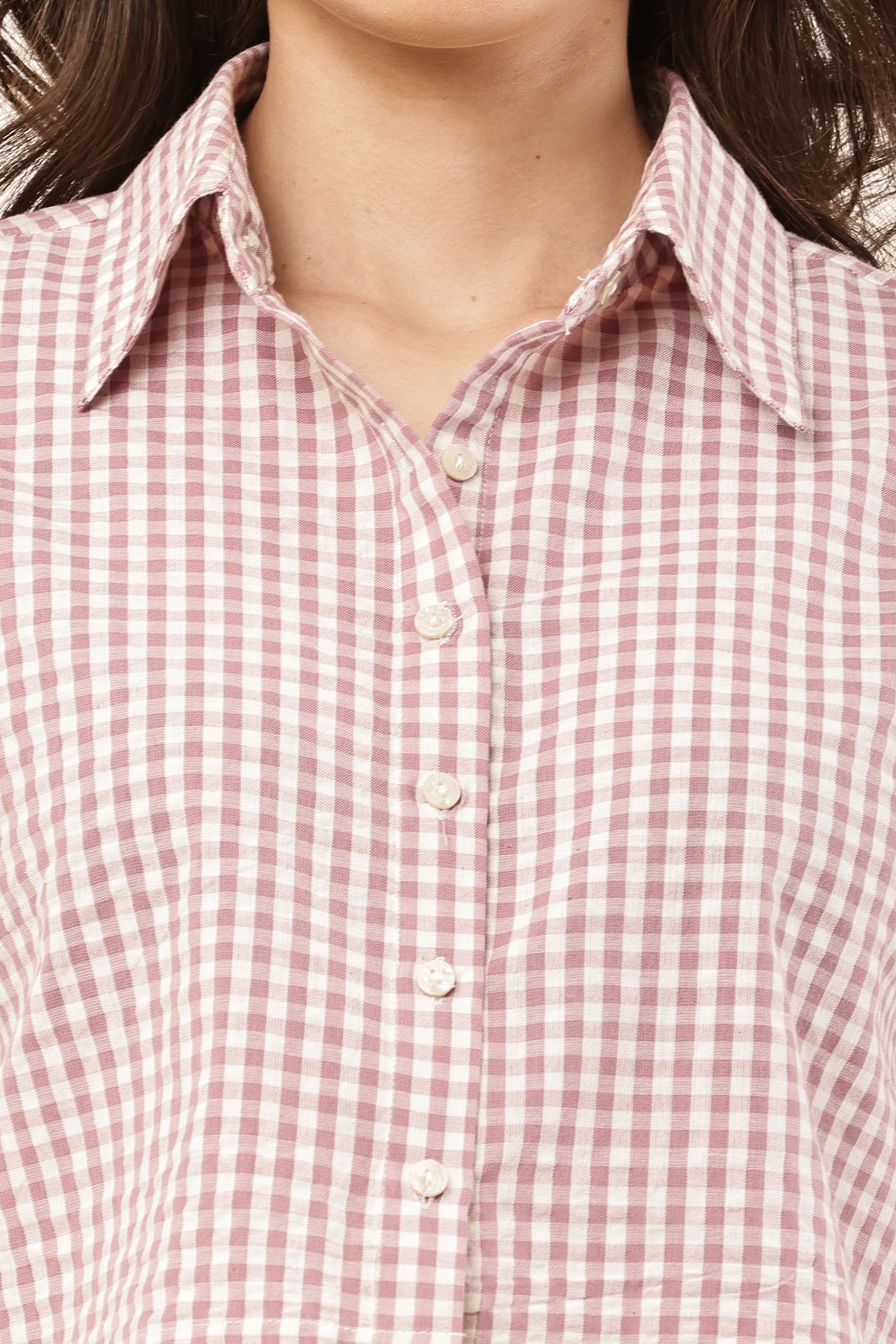 Close-up of a person wearing a pink and white checkered shirt.