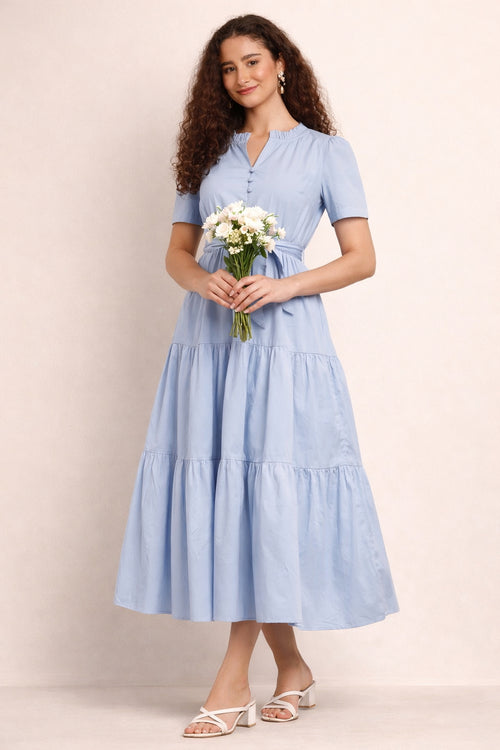 Woman wearing a light blue dress holding flowers against a beige background