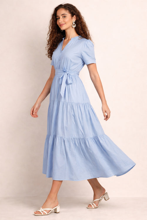 Woman wearing a light blue mazi dress against a beige background