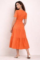 Woman wearing an orange maxi dress against a white background