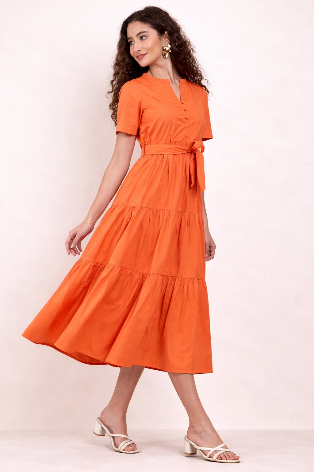 Woman wearing an orange maxi dress against a white background