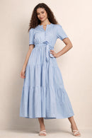 Woman wearing a light blue maxi dress against a beige background