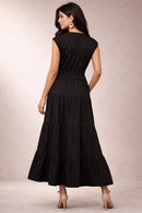 Woman wearing a black tiered dress against a neutral background