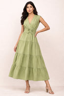 Woman wearing a green mxi dress with a plain background