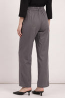 A model from the back wearing gray wide-leg trousers, a black long-sleeve top, and black pointed-toe mule heels against a plain light background.