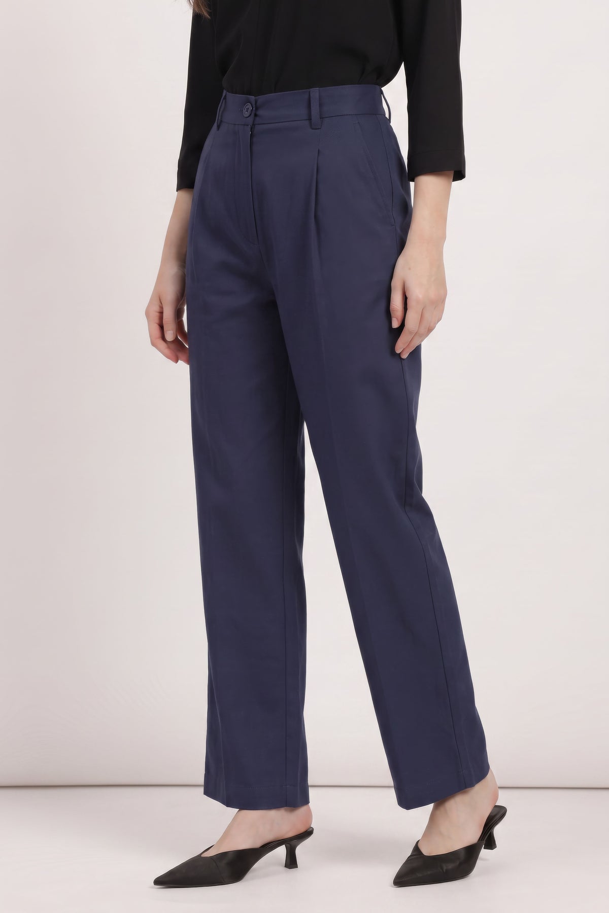 A model wearing navy blue high-waisted wide-leg trousers, paired with a black long-sleeve top and black pointed-toe mule heels, shown from the waist down against a plain light background.