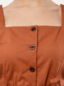 Close-up of a terracotta brown top with a square neckline, three dark brown buttons, and a visible skin line at the neck.
