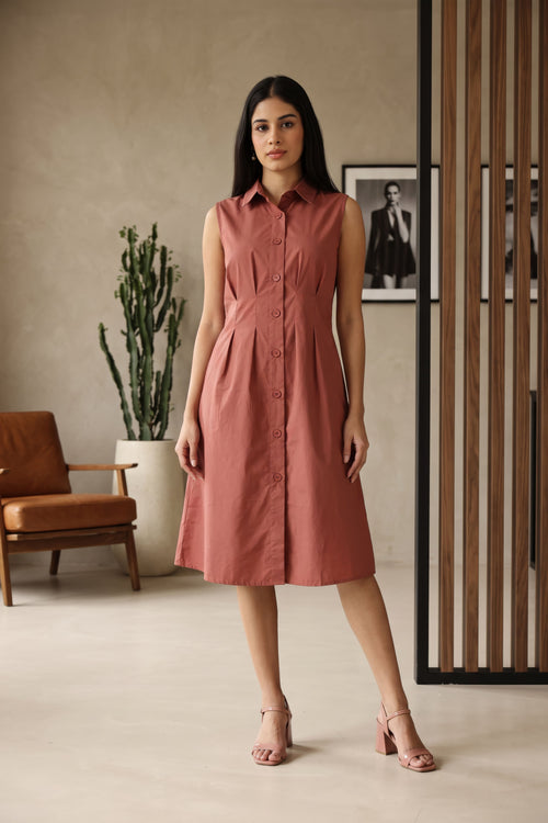 A woman modeling a Rose gold sleeveless maxi dress with a spread collar neckline and flared skirt, standing in front of a beige stone archway background.